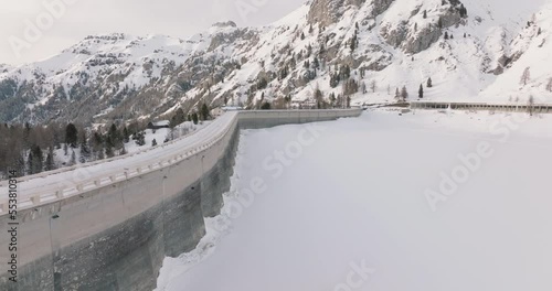Aerial view of Dam on Passo Fedaia in the Alps. Snow covered lake. Barrier lake seen from above