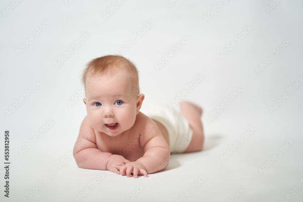 an infant lying on its stomach looking intently into the camera with its mouth open against a white background an infant lying on its stomach looking intently into the camera with its mouth open against a white background