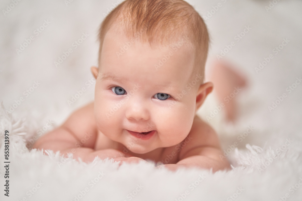portrait of an infant looking into the camera with sly emotion on a soft blanket portrait of an infant looking into the camera with sly emotion on a soft blanket