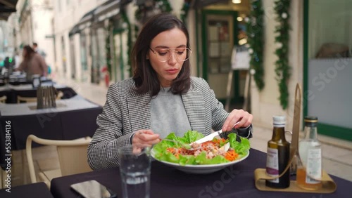 Business woman eat tuna salad outdoor street cafe during business launch time. Caucasian female business person healthy food outside restuarant. Break for energy, vitamins and refreshness.  photo