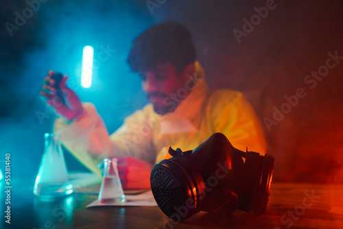 Male chemist adding reagent into flask photo
