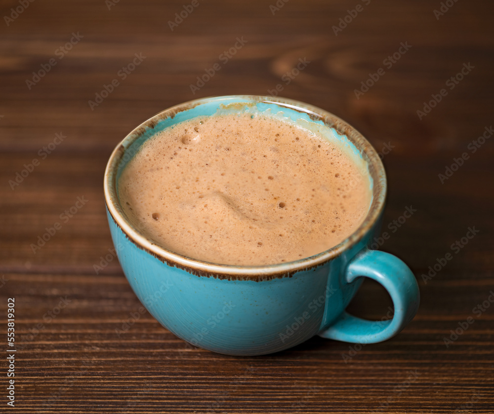 Obraz premium Big blue cup with cappuccino on wooden background