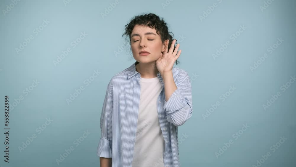 I cant hear you. Female girl trying hear you, looking confused and frowning, keeping arm near ear for louder voice, asking to repeat, to hear information, deafness. Cheerful woman on blue background