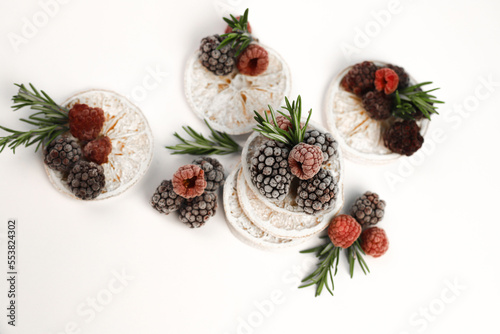 sweet delicious berry dessert of white dried oranges garnished with juicy raspberries and blackberries and rosemary sprigs on a white background. for signboards, labels, postcards, leaflets, shop bann