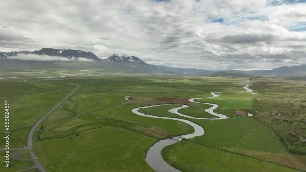 Winding river in Iceland aerial shot farmlands in countryside cloudy day