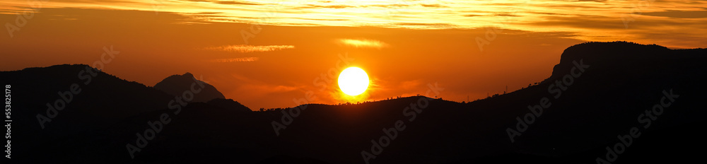 Sunset behind hills and trees, clouds looks like solar storm