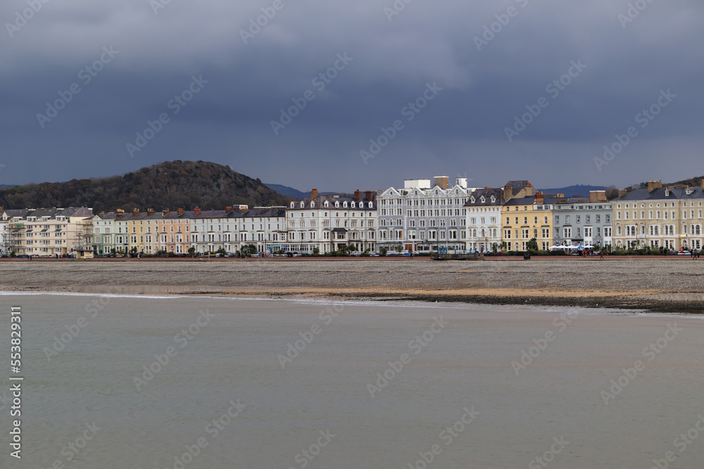A seaside tourist town with a promenade. A city by the ocean with a cloudy sky before rain. Llandudno, Wales, United Kingdom