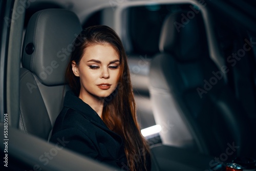 a stylish, luxurious woman is sitting in a black car at night in the passenger seat, relaxing with her eyes closed. Topics of safe driving on the roads © SHOTPRIME STUDIO