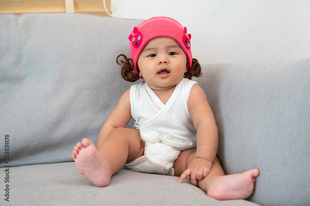Portrait of baby girl sitting on sofa at home, family, child, childhood and parenthood concept Portrait of baby girl sitting on sofa at home, family, child, childhood and parenthood concept