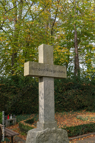 schönes altes Steinkreuz mit Bibelspruch auf einem Friedhof in Hamburg