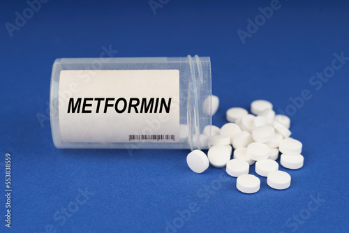 On a blue surface are pills and a dusty jar with the inscription - Metformin photo