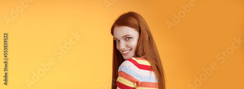 Tenderness, romance, seduction concept. Attractive cheeky flirty young redhead daring girl turn behind look shoulder camera smiling silly coquettish giggle express sympathy affection