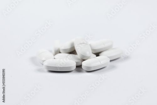 many white oval medical tablets for humans and animals, medicinal antibiotics pills medicine closeup