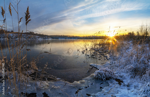 Sunset in winter on the shore of a freezing lake.