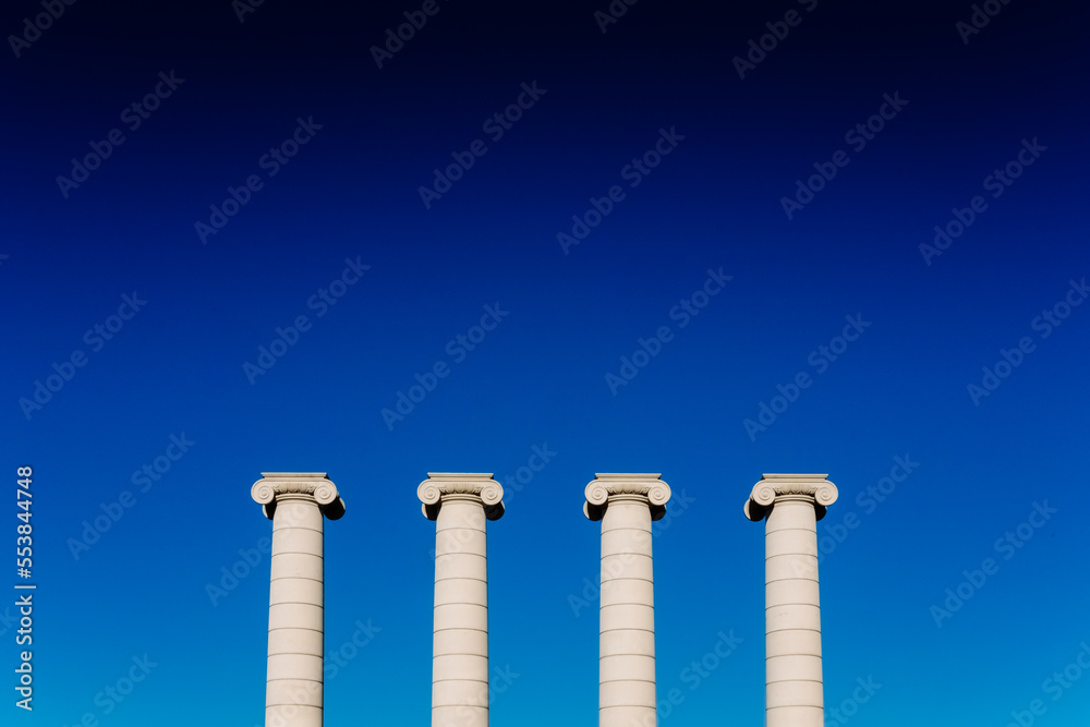 Four classical ionic columns, isolated on blue sky background
