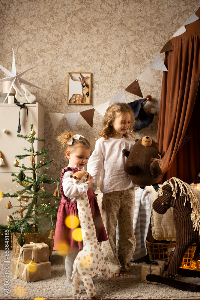 two sisters playing at children's room on Christmas decorated home