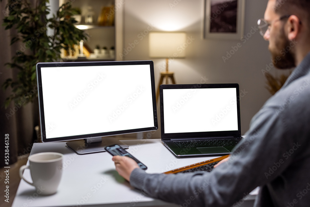 Male employee working with laptop and blank template on display, looking at isolated mockup screen. Using white copyspace background on laptop at home desk. Male employee working with laptop and blank template on display, looking at isolated mockup screen. Using white copyspace background on laptop at home desk.
