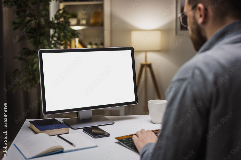 Backview of male freelance software developer working on laptop from home, developing project.