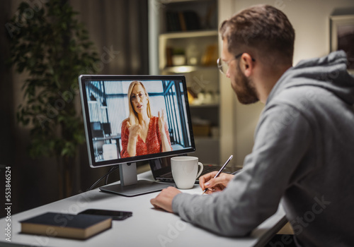 Obraz na płótnie Young businessman having videochat with colleague and making notes of ideas, brainstorming w salonie
