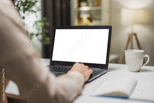 Backview of male in front of white laptop screen and opened books lying on the desk