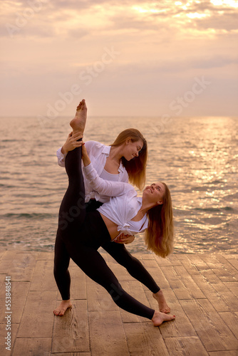 Wallpaper Mural dancing couple two woman twins training in morning on beach. Two sisters twin girls in identical clothes on ocean background Torontodigital.ca