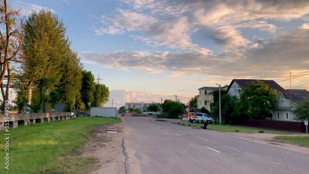 Beautiful city sunset among one-story houses. Air clouds on the blue sky. Road with traffic signs. Beautiful city sunset among one-story houses. Air clouds on the blue sky. Road with traffic signs.