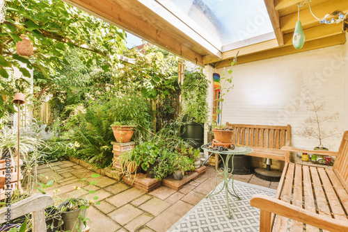 Fotografia a patio with lots of plants and pots on the ground in front of a white brick wal