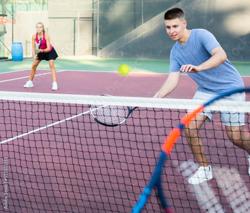 Concentrated young man tennis player hitting ball with a racket