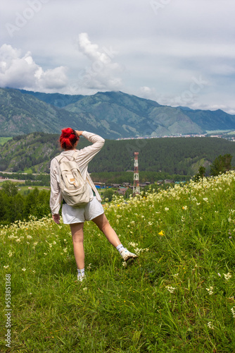 One girl standing alone on road and looking back on mountains