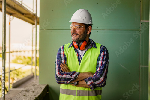 Portrait of men in 40s, construction worker. He is standing in construction and posing for camera.