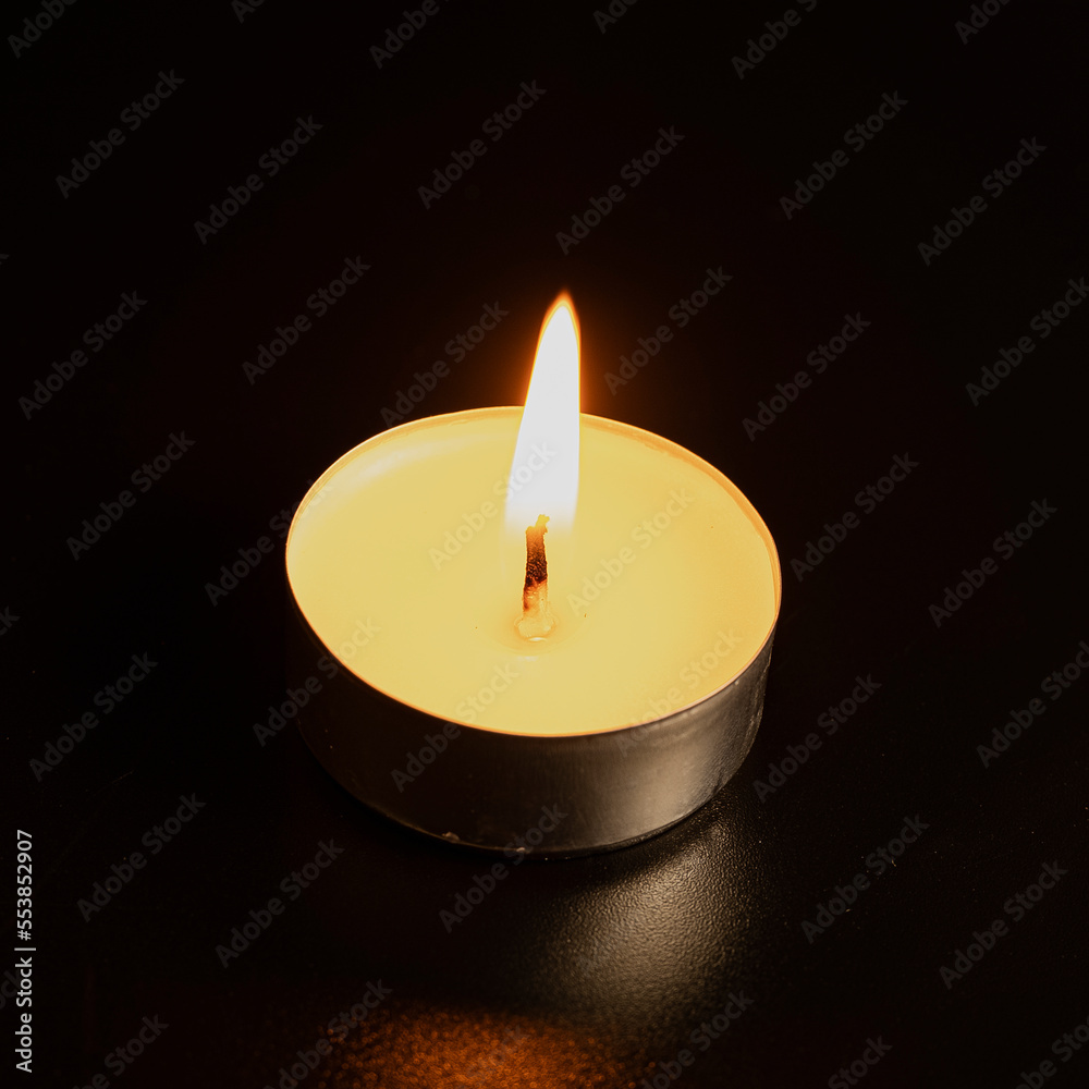 Candles in the dark. Round floating candle. candles in an aluminum case. burning aluminum tea candle isolated on black background. romantic atmosphere Candles in the dark. Round floating candle. candles in an aluminum case. burning aluminum tea candle isolated on black background. romantic atmosphere