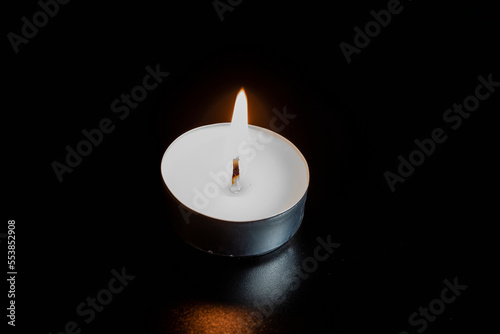 Candles in the dark. Round floating candle. candles in an aluminum case. burning aluminum tea candle isolated on black background. romantic atmosphere
