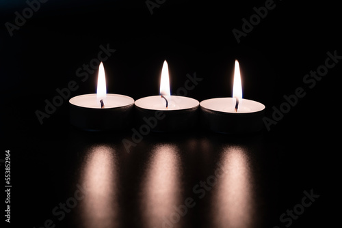 Candles in the dark. Round floating candle. candles in an aluminum case. burning aluminum tea candle isolated on black background. romantic atmosphere