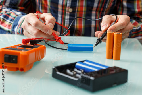 Electrician measuring battery voltage with a multimeter.