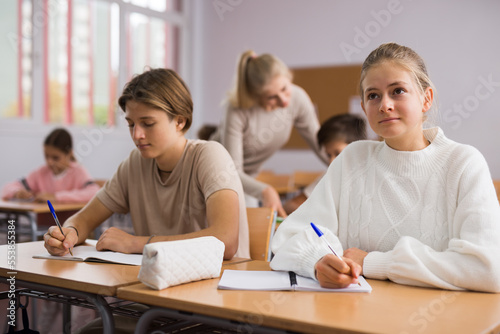 Portrait of teenage school girl and boy sitting together in classroom during lesson in secondary school