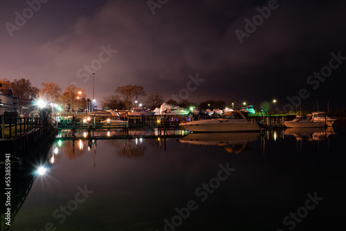 Marina at night with boats and colorful lights.