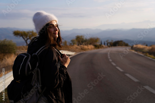 Female hiker with backpack travel in mountains,walk on road