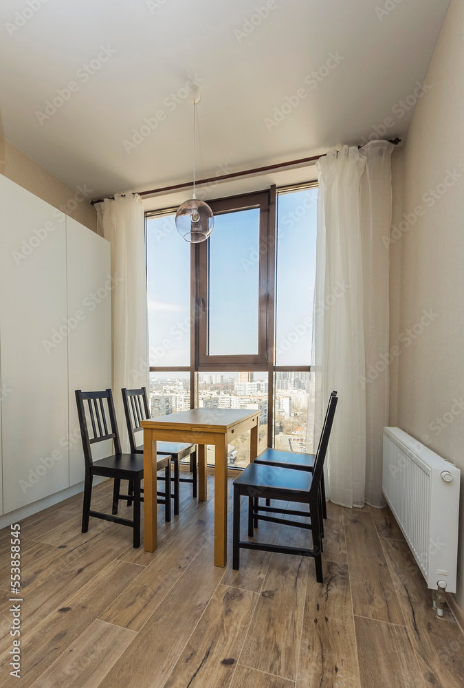 Fototapeta premium View of a table with chairs by the window in a new room after renovation