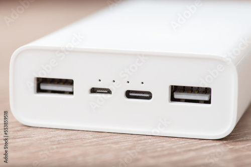 Close up shot of white modern powerbank on the table. External battery with four usb ports - type A, micro usb and type C