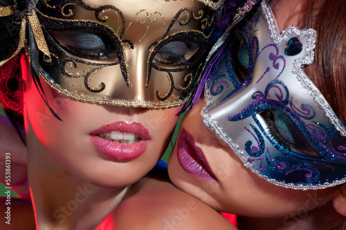 Couple of sensual women with colorful makeup and carnival masks