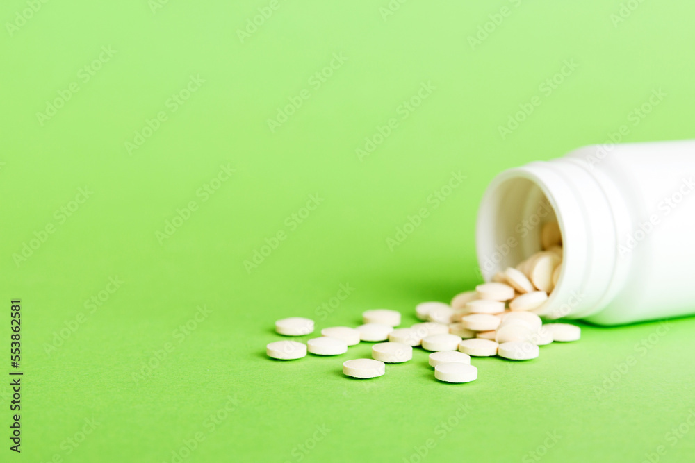 Medicine bottle and white pills spilled on a light background. Medicines and prescription pills flat lay background. White medical pills and tablets spilling out of a drug bottle Medicine bottle and white pills spilled on a light background. Medicines and prescription pills flat lay background. White medical pills and tablets spilling out of a drug bottle