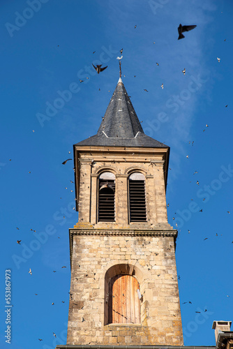 Birds flying around the church tower in the town of Florac in France photo