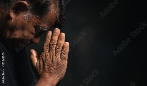 Print op canvas Elderly Asian man bowed his head praying to God on a black background at home