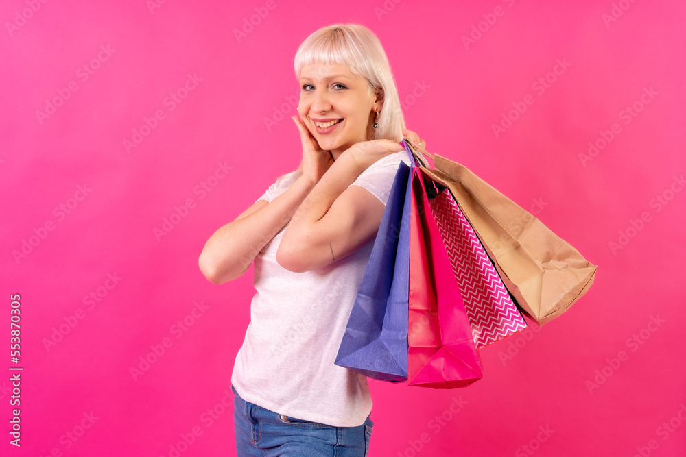 Very happy with shopping bags in the offers, blonde caucasian girl in studio on pink background Very happy with shopping bags in the offers, blonde caucasian girl in studio on pink background