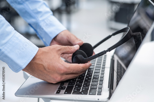 A man puts a headset on a laptop keyboard in the office.