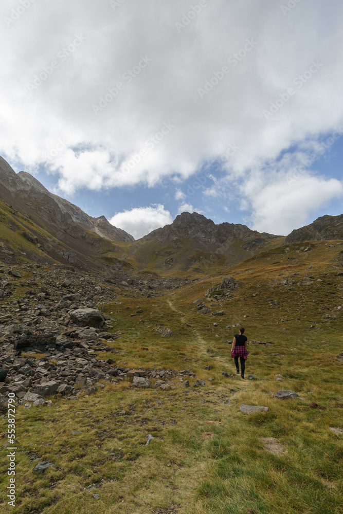 Hiking woman at Col de Lurien on beautiful mountain pass in the Pyrenees mountains on a sunny autumn day, Artouste, Nouvelle-Aquitaine, France