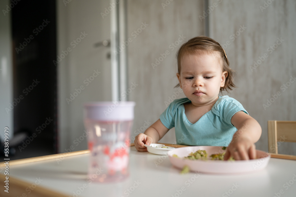 one girl small caucasian child one year old eat at the table at home one girl small caucasian child one year old eat at the table at home
