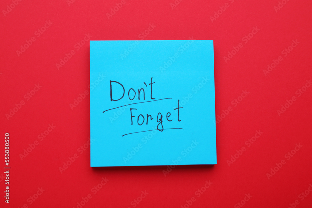Paper note with phrase Don't Forget on red background, top view Paper note with phrase Don't Forget on red background, top view