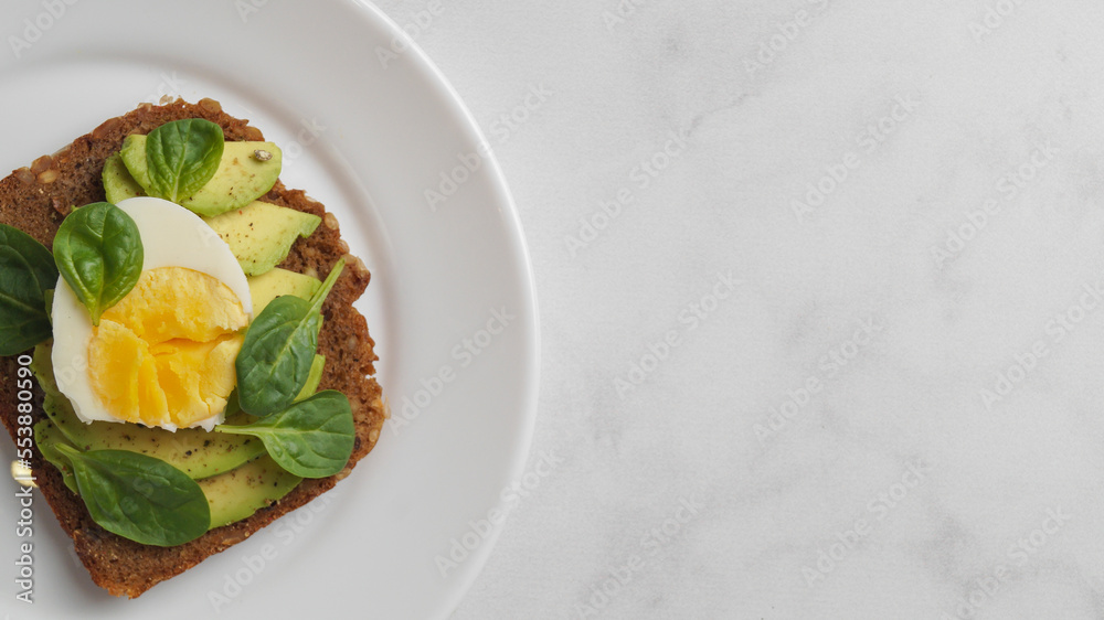 Tasty sandwich with boiled egg and avocado on white marble table, top view. Space for text