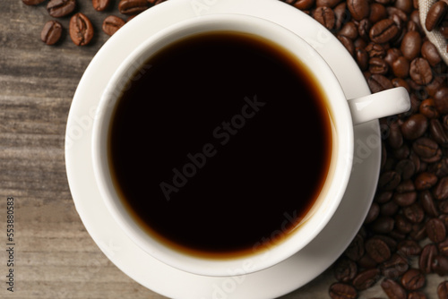 Cup of aromatic coffee on wooden table, top view